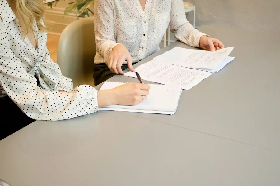 Deux personnes relisent et signent des documents autour d'une table